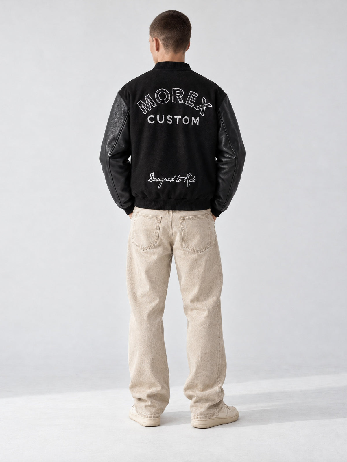 Homme de dos portant le blouson teddy varsity noir Morex Custom avec manches en cuir et broderie dos Designed to Ride