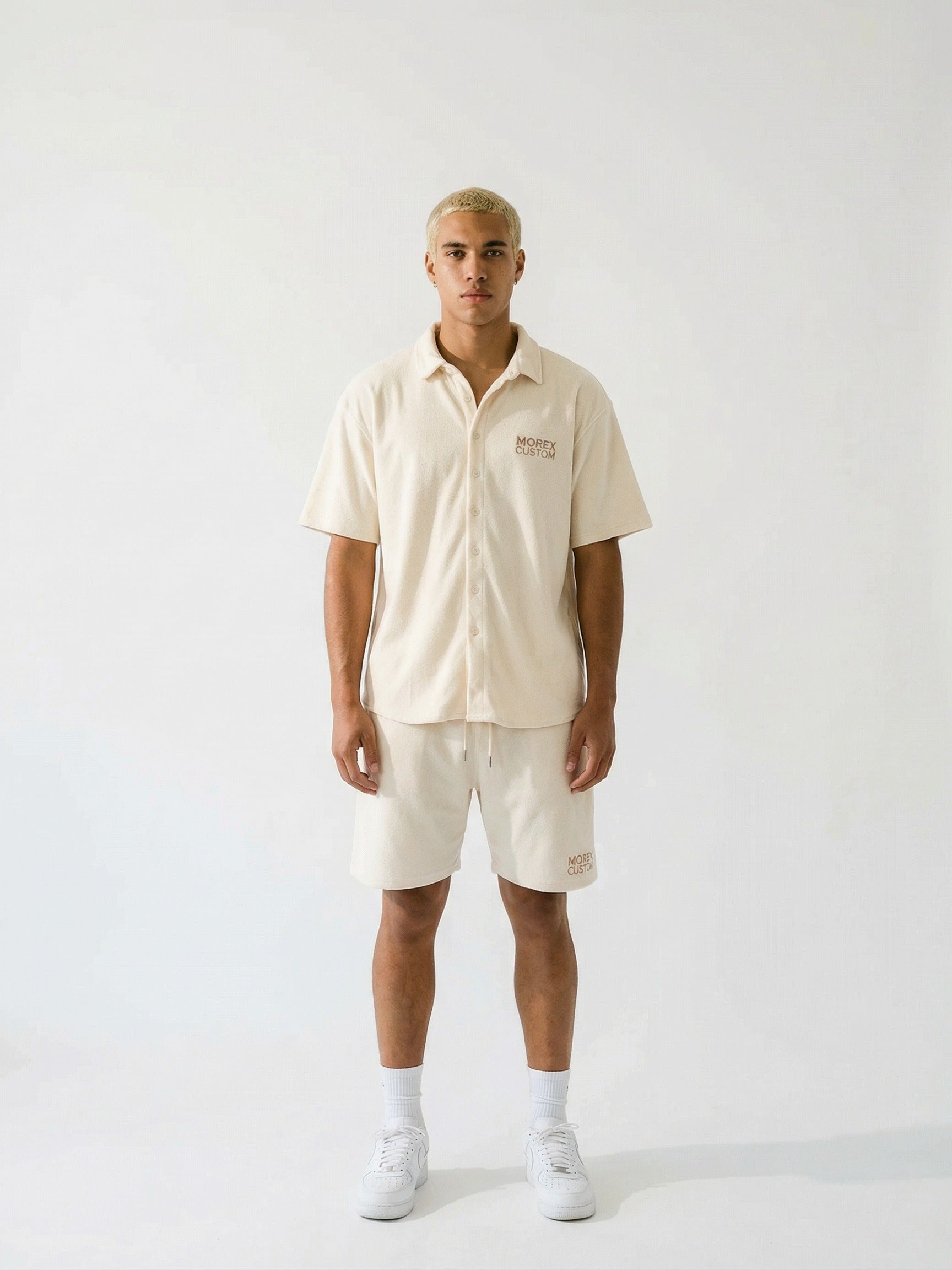 Mannequin portant un ensemble lifestyle Morex Custom beige composé d'une chemise à manches courtes boutonnée et d'un short assorti sur fond blanc.