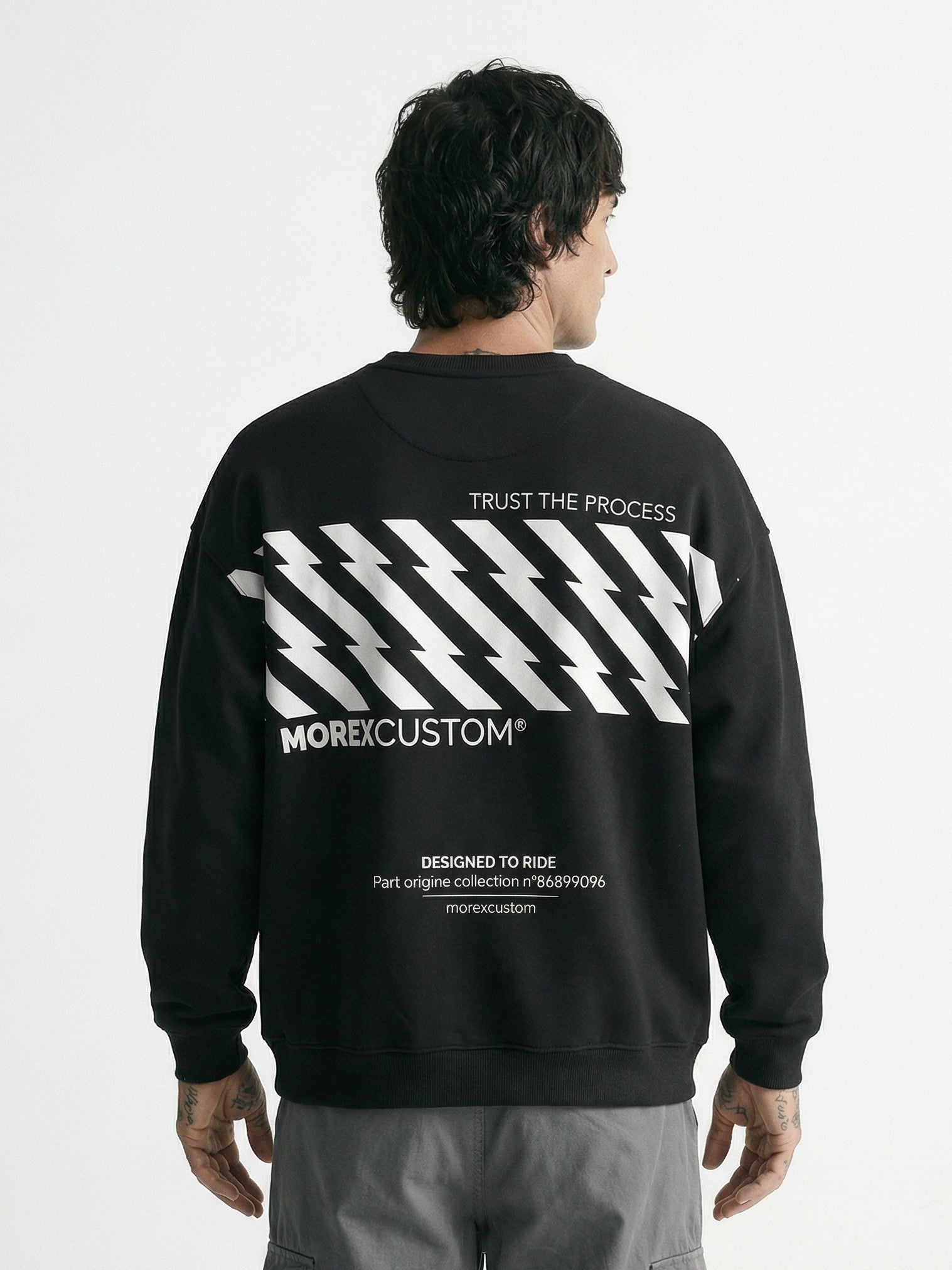 Back view of a man wearing a black Morex Custom sweatshirt with a white glitch-effect diagonal stripe graphic and 'Trust the Process' text.