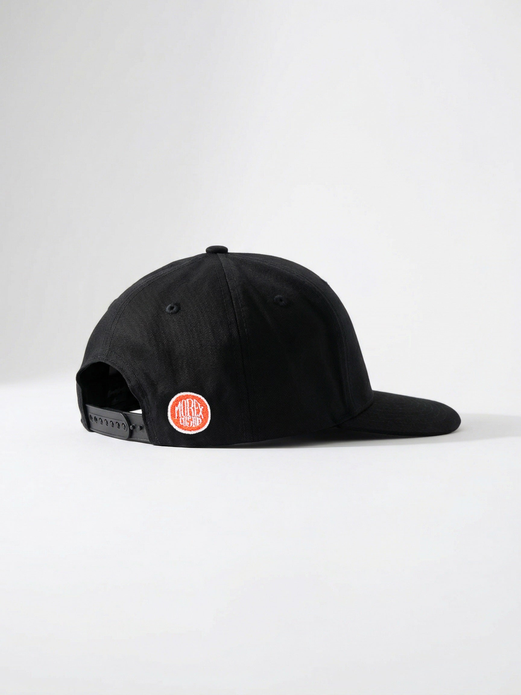 Profil latéral d'une casquette noire Morex Custom avec un petit écusson circulaire orange sur le côté arrière.