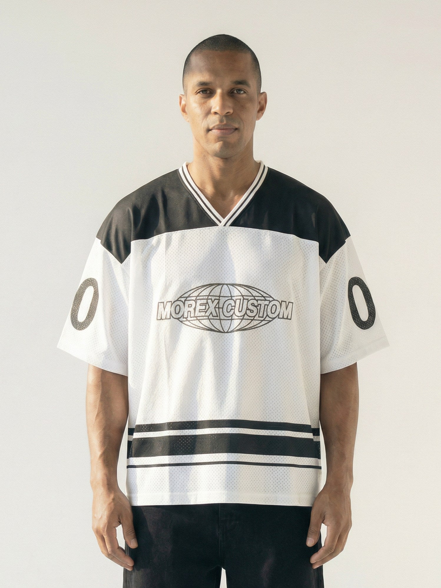 Homme portant un maillot de hockey Morex Custom noir et blanc avec logo globe central et bandes horizontales, style lifestyle moto.