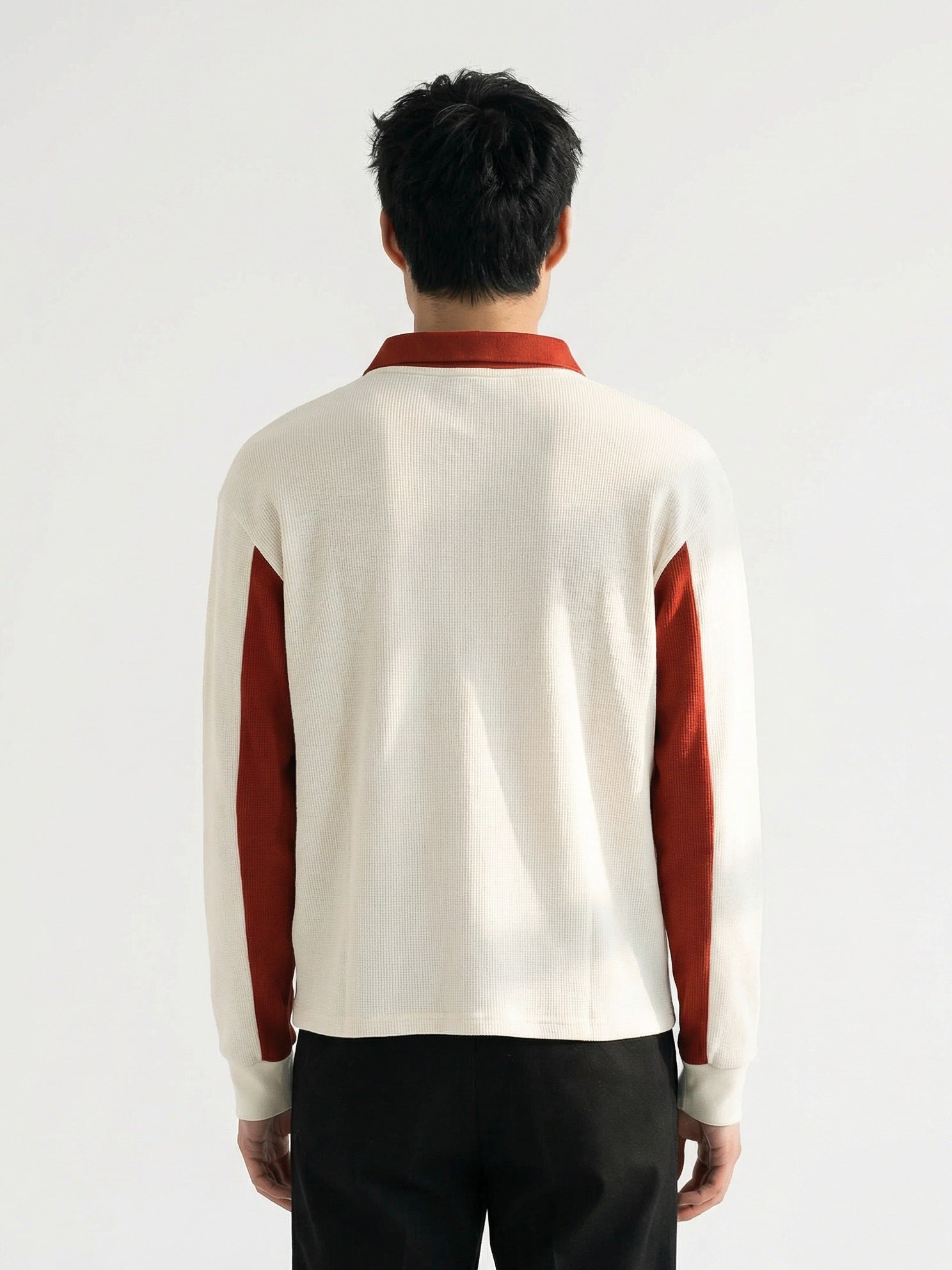 Vue arrière d'un homme portant un polo Morex Custom en tricot blanc cassé avec des empiècements rouille sur les manches et le col, style moto lifestyle.