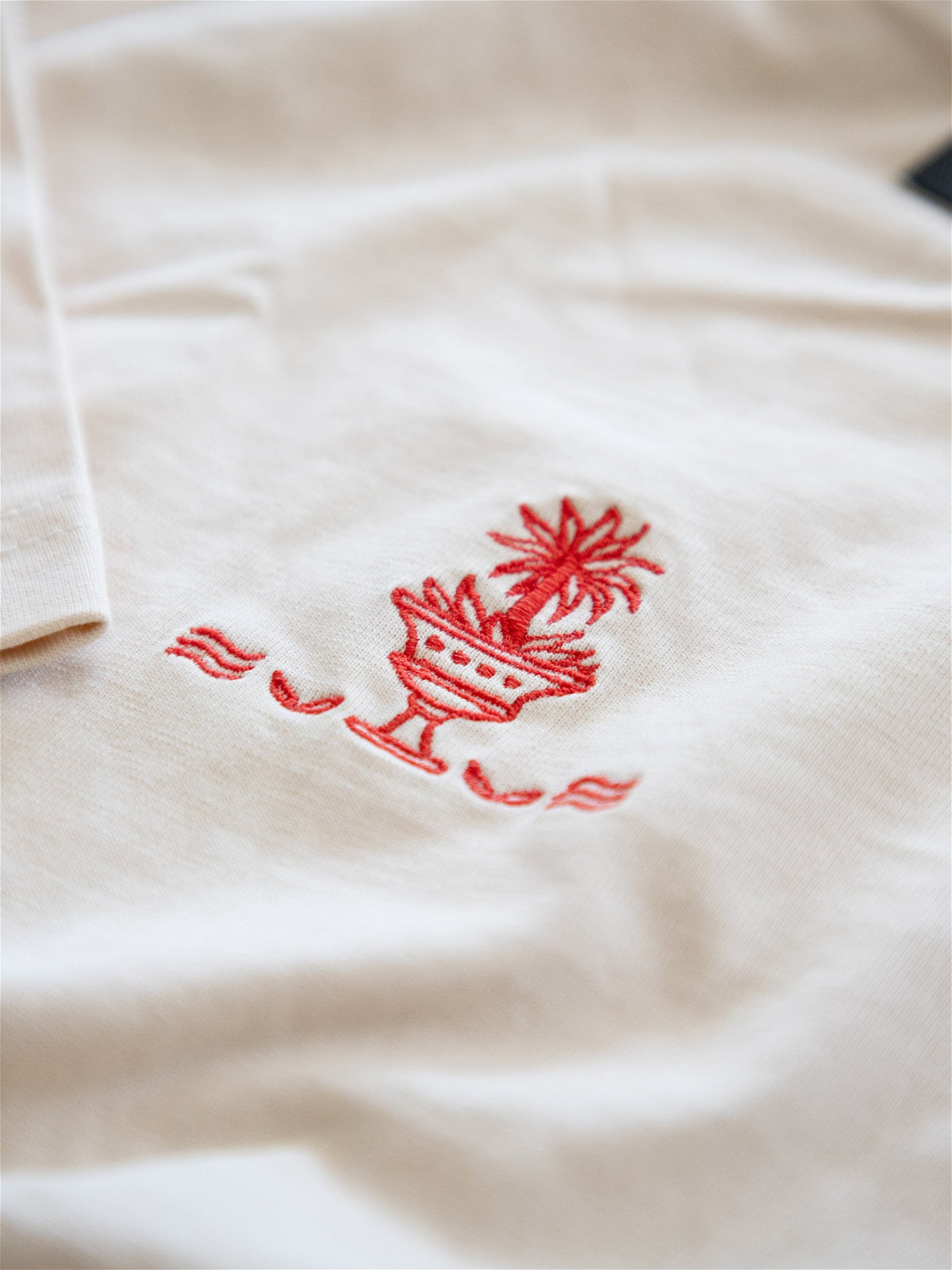 Gros plan sur la broderie rouge palmier sur t-shirt écru en coton Morex Custom, esprit moto et lifestyle.