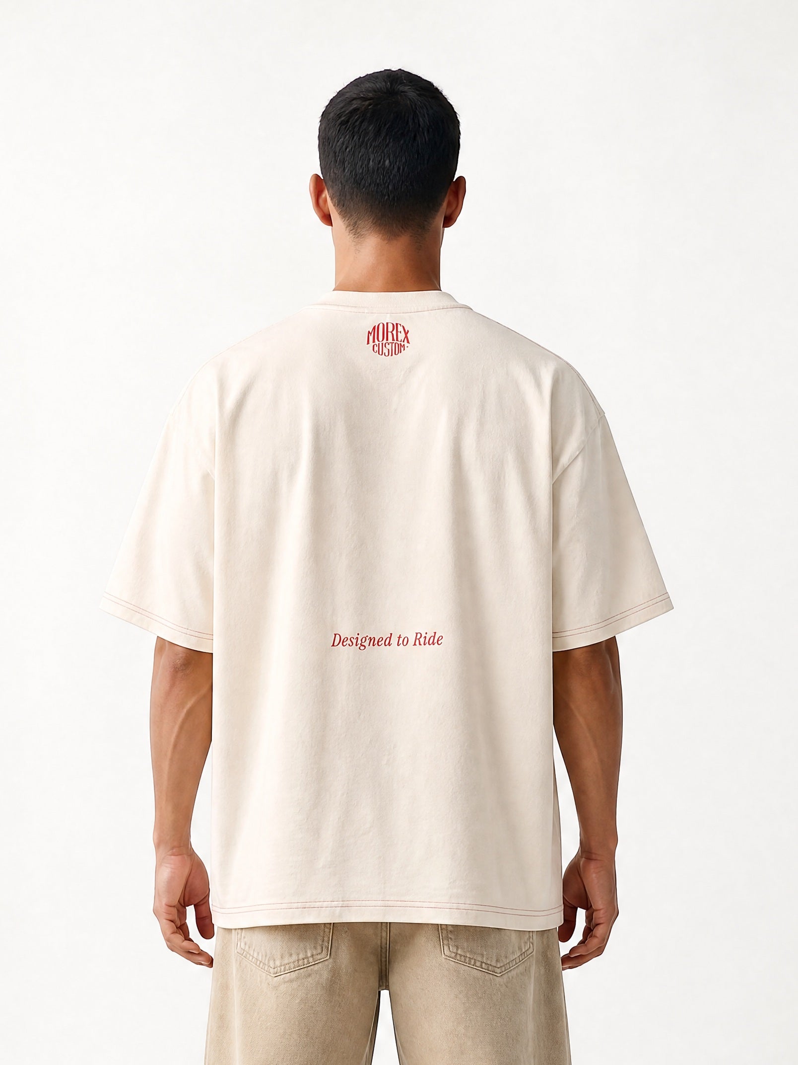Vue de dos d'un homme portant un t-shirt oversize crème avec logo rouge et un pantalon large beige de la collection lifestyle Morex Custom.
