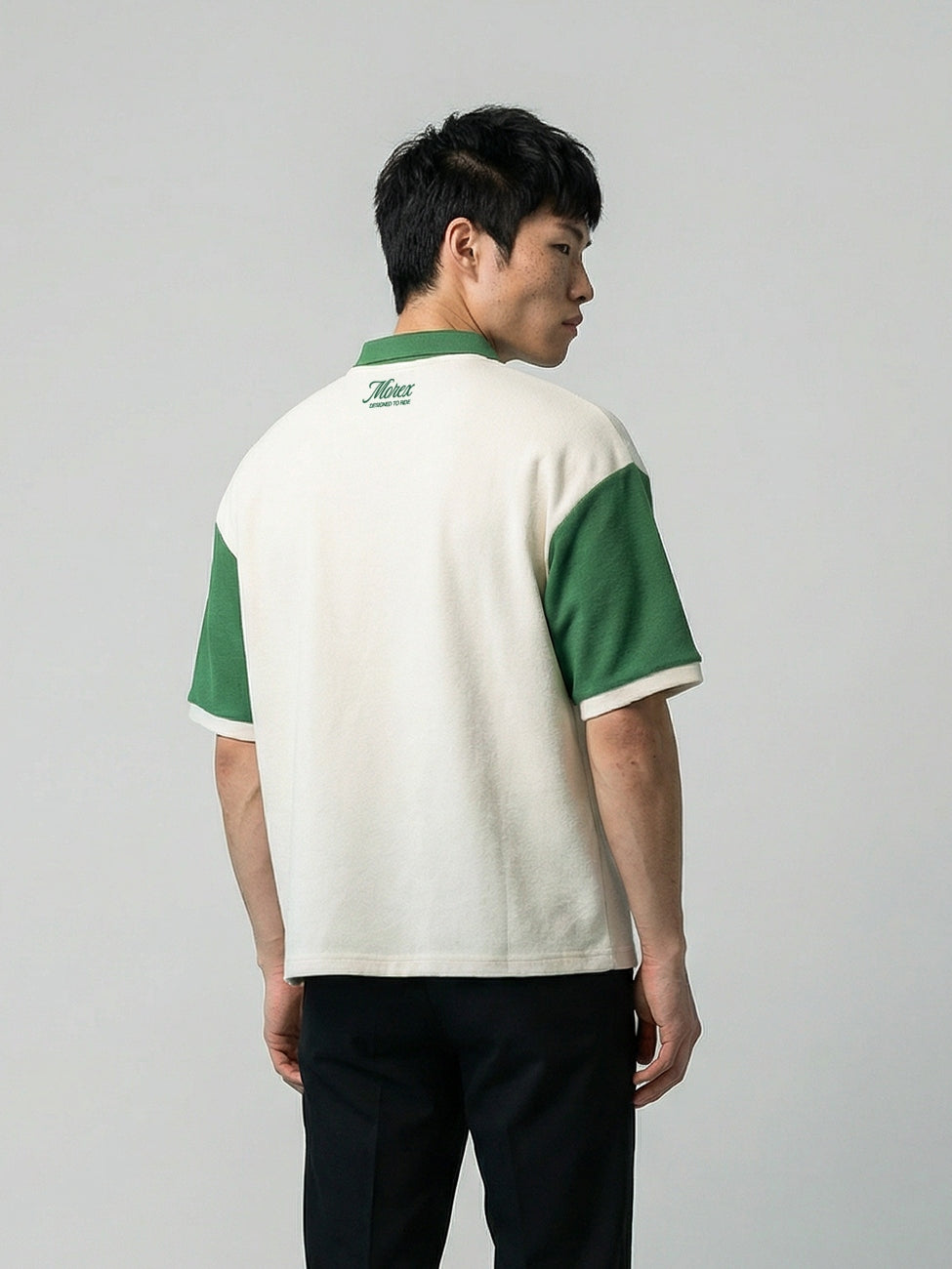 Homme de dos portant un polo bicolore crème et vert de la collection lifestyle Morex Custom avec un pantalon noir.