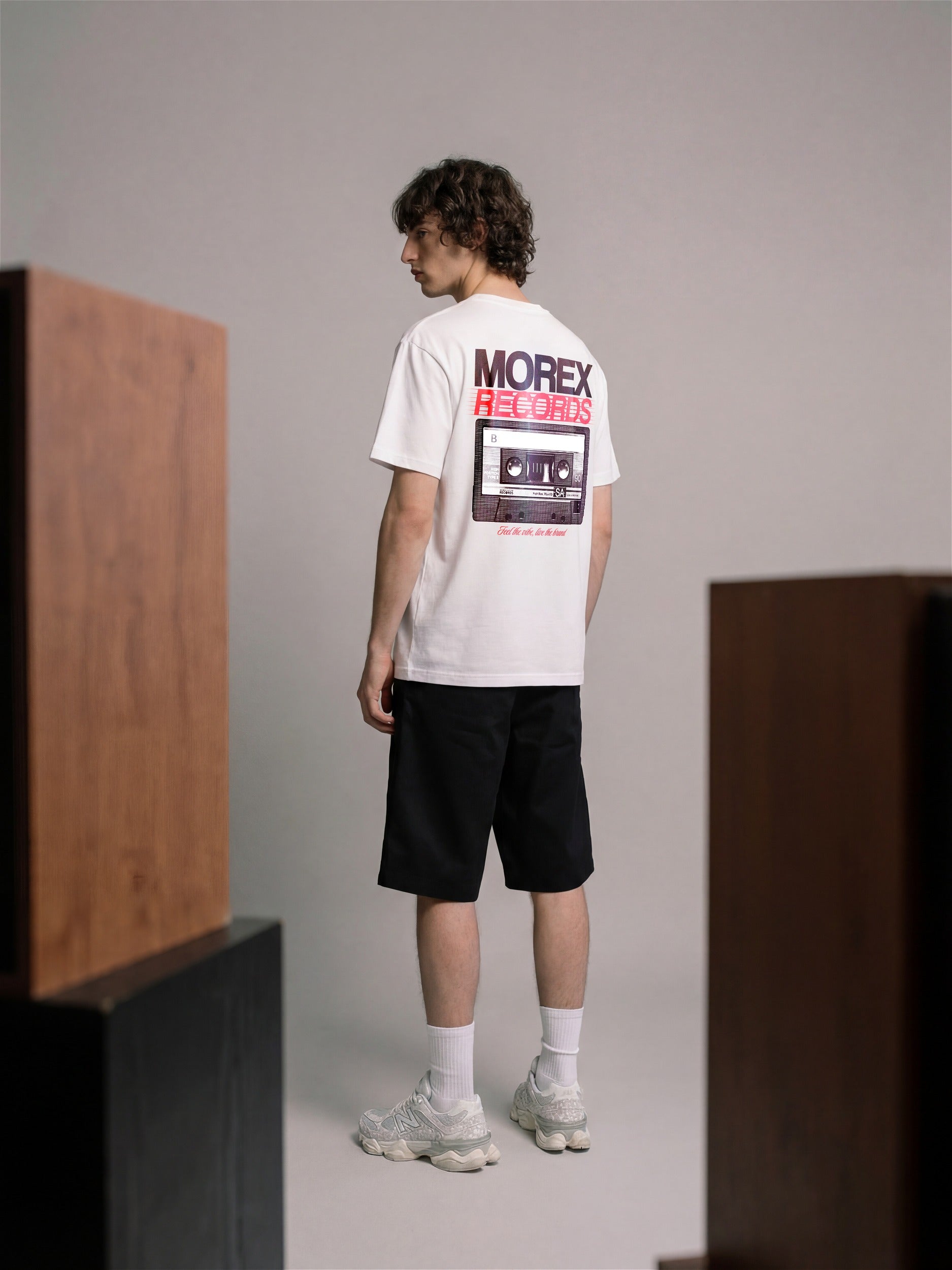 T-shirt blanc Morex Custom avec le graphisme Morex Records imprimé au dos, porté par un homme dans un style streetwear avec short noir et baskets.