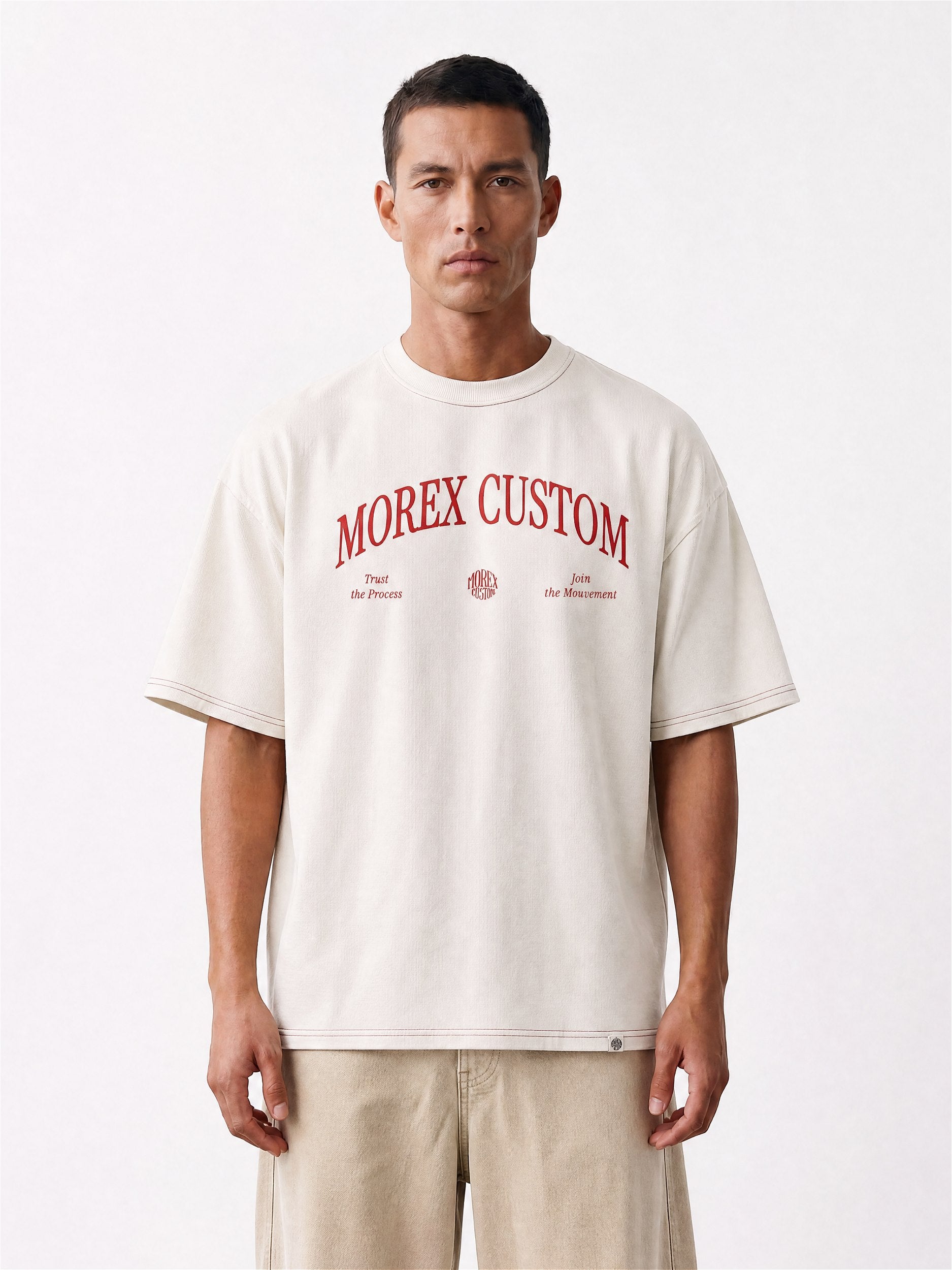 Homme portant un t-shirt Morex Custom de couleur crème avec le logo arqué rouge sur la poitrine, style lifestyle moto et décontracté.