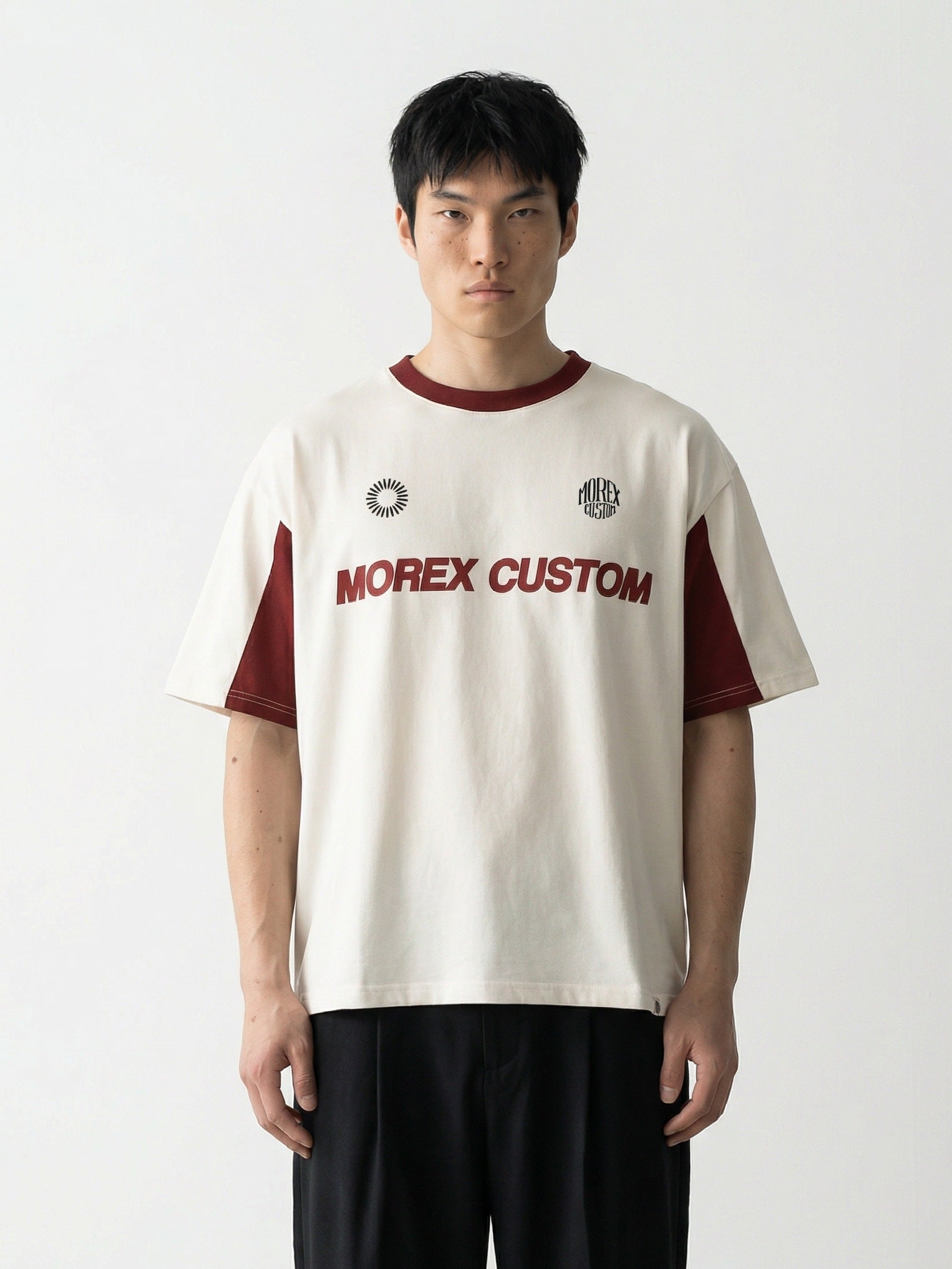 Un homme portant un t-shirt Morex Custom de style moto lifestyle en coton crème avec des empiècements bordeaux et le logo de la marque sur la poitrine.