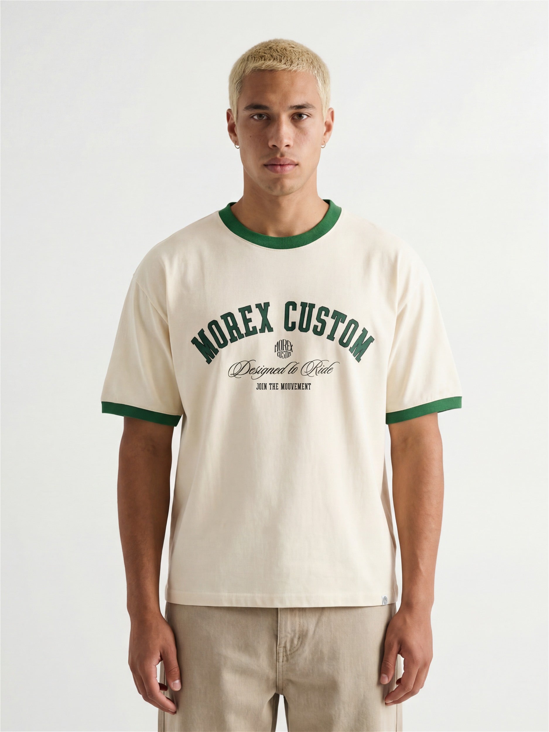 Homme portant un t-shirt ringer Morex Custom blanc cassé avec col et bordures de manches verts, arborant le logo graphique Morex Custom Designed to Ride.