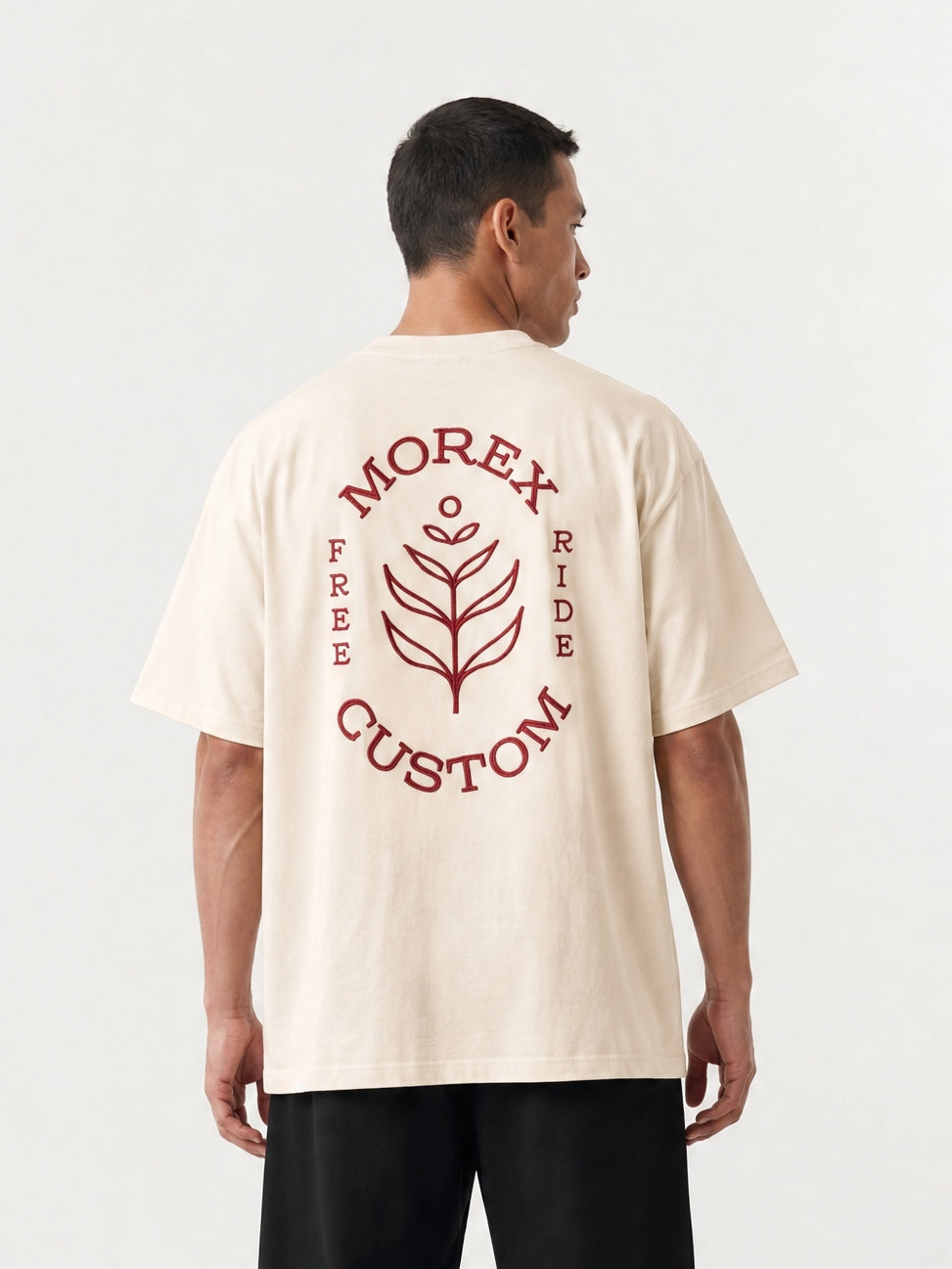 Homme de dos portant un t-shirt oversize beige crème de la marque Morex Custom avec un grand logo graphique rouge et un pantalon noir large.