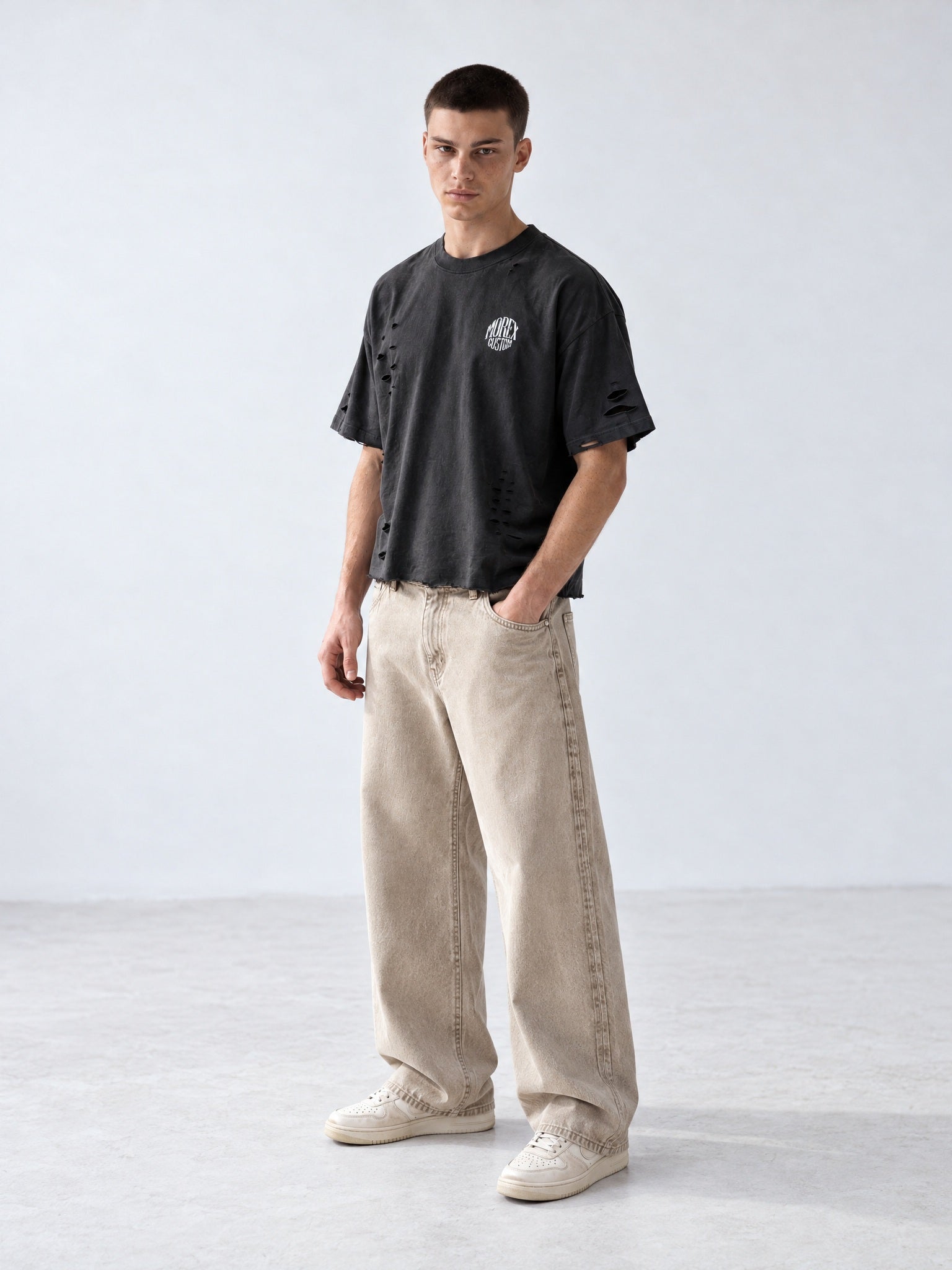 Homme portant un t-shirt oversize noir délavé effet vieilli et usé Morex Custom avec un jean ample beige, look streetwear moto lifestyle.