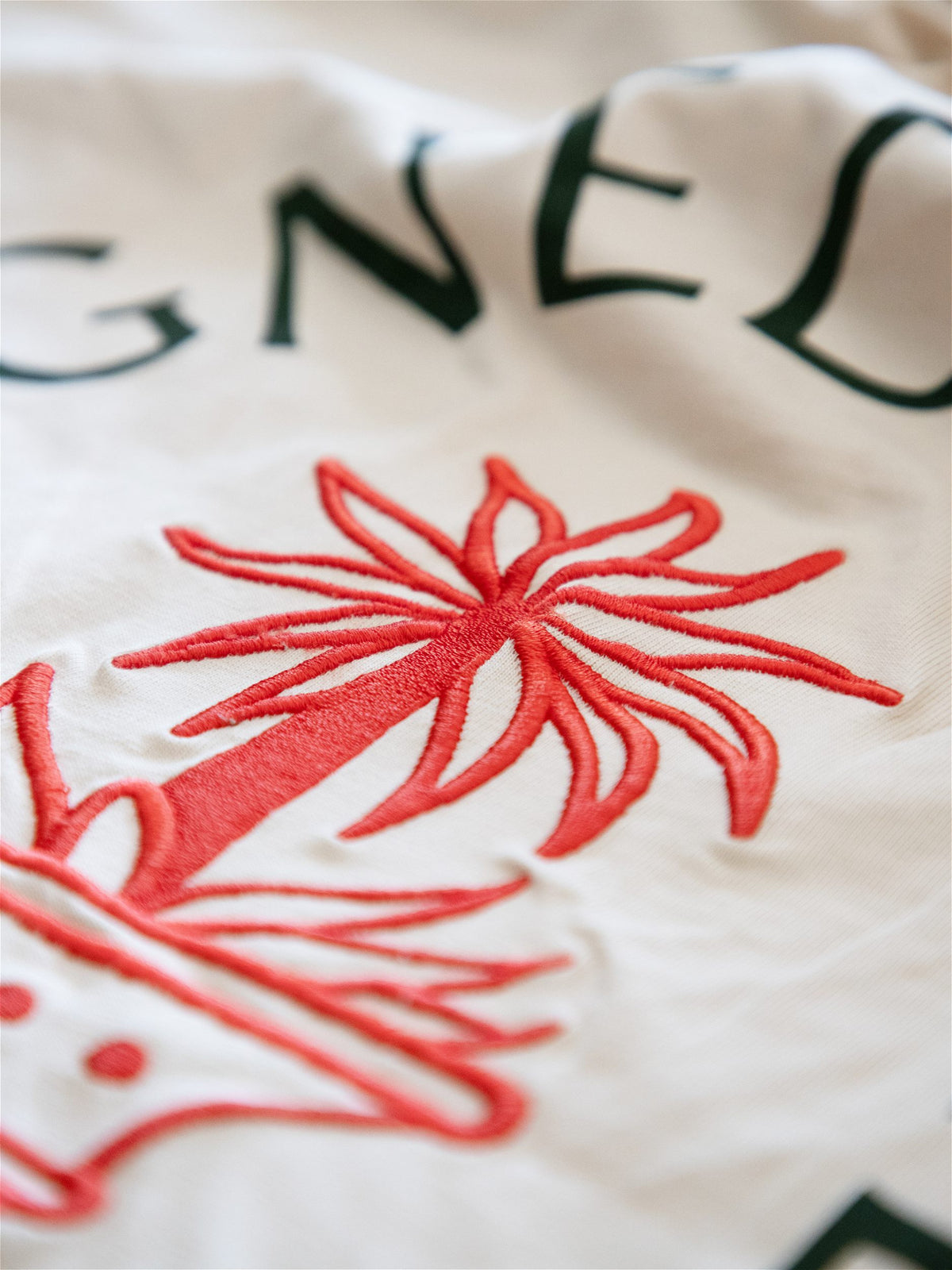 Gros plan sur les finitions soignées de la broderie palmier rouge en relief sur un t-shirt Morex Custom.