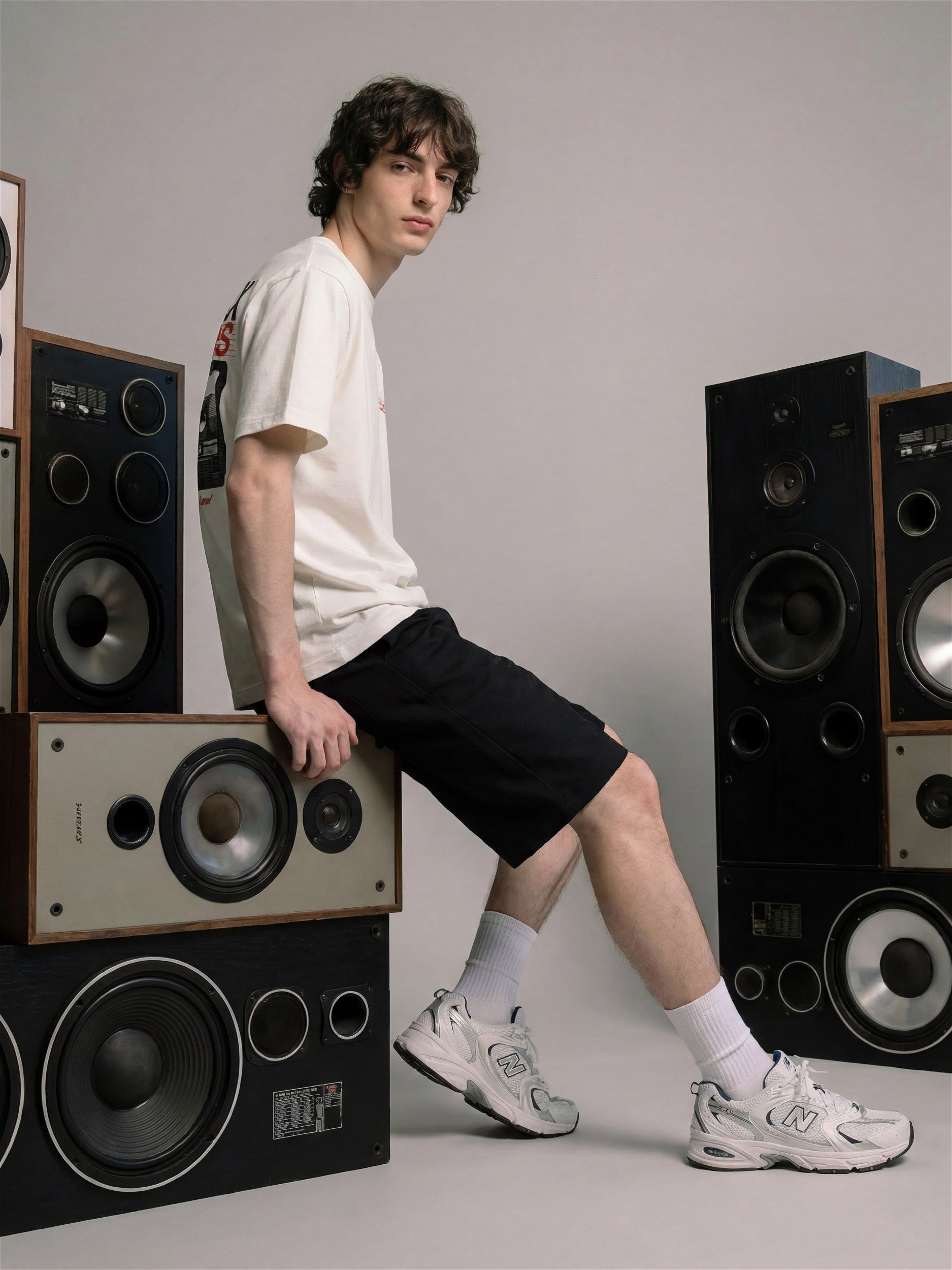 Homme portant un t-shirt blanc et un short noir de la collection Morex Custom, assis au milieu d'enceintes vintage.