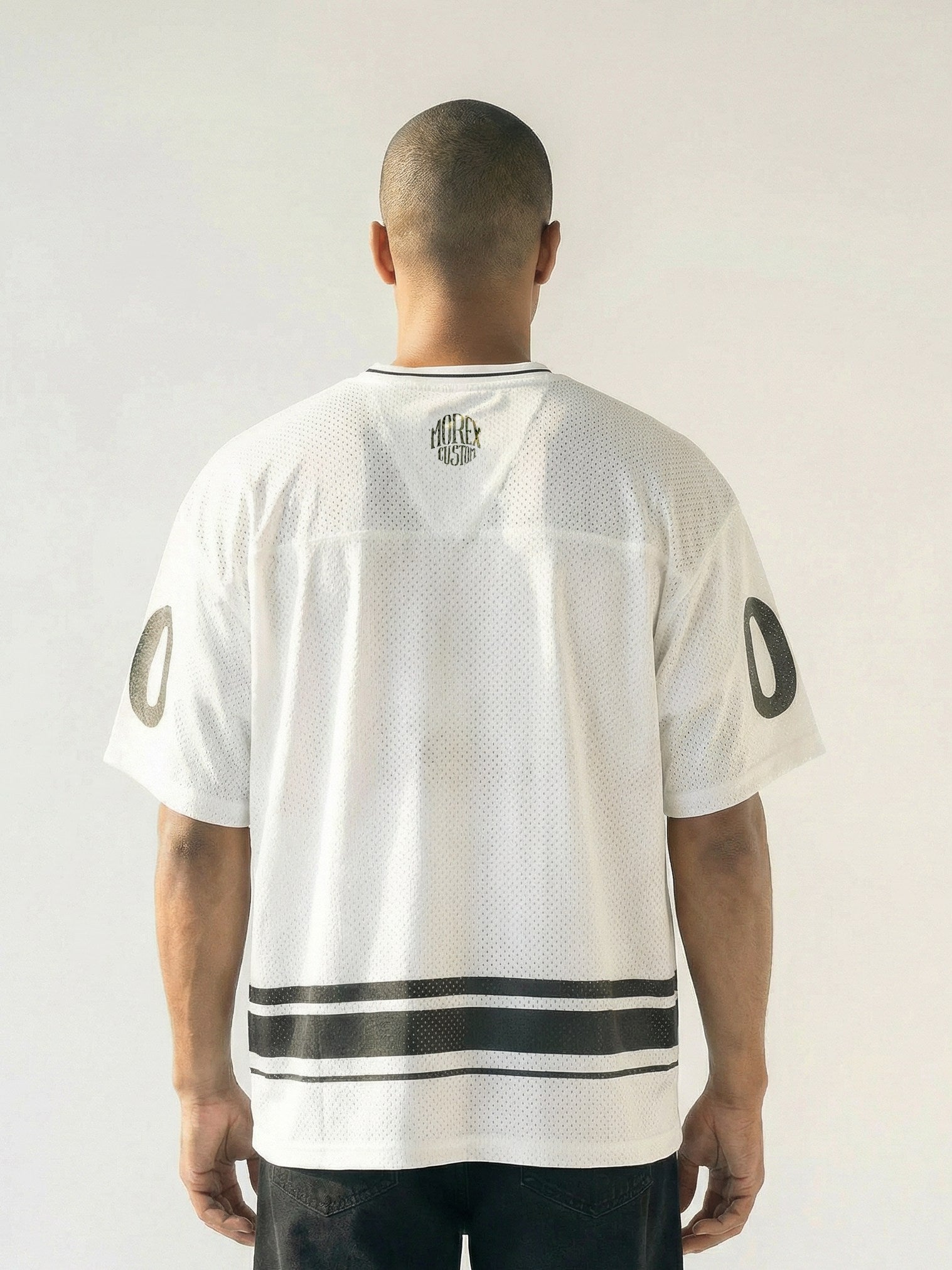 Vue de dos d'un homme portant le maillot en mesh blanc Morex Custom avec rayures noires à la taille et logo au col, style lifestyle moto.