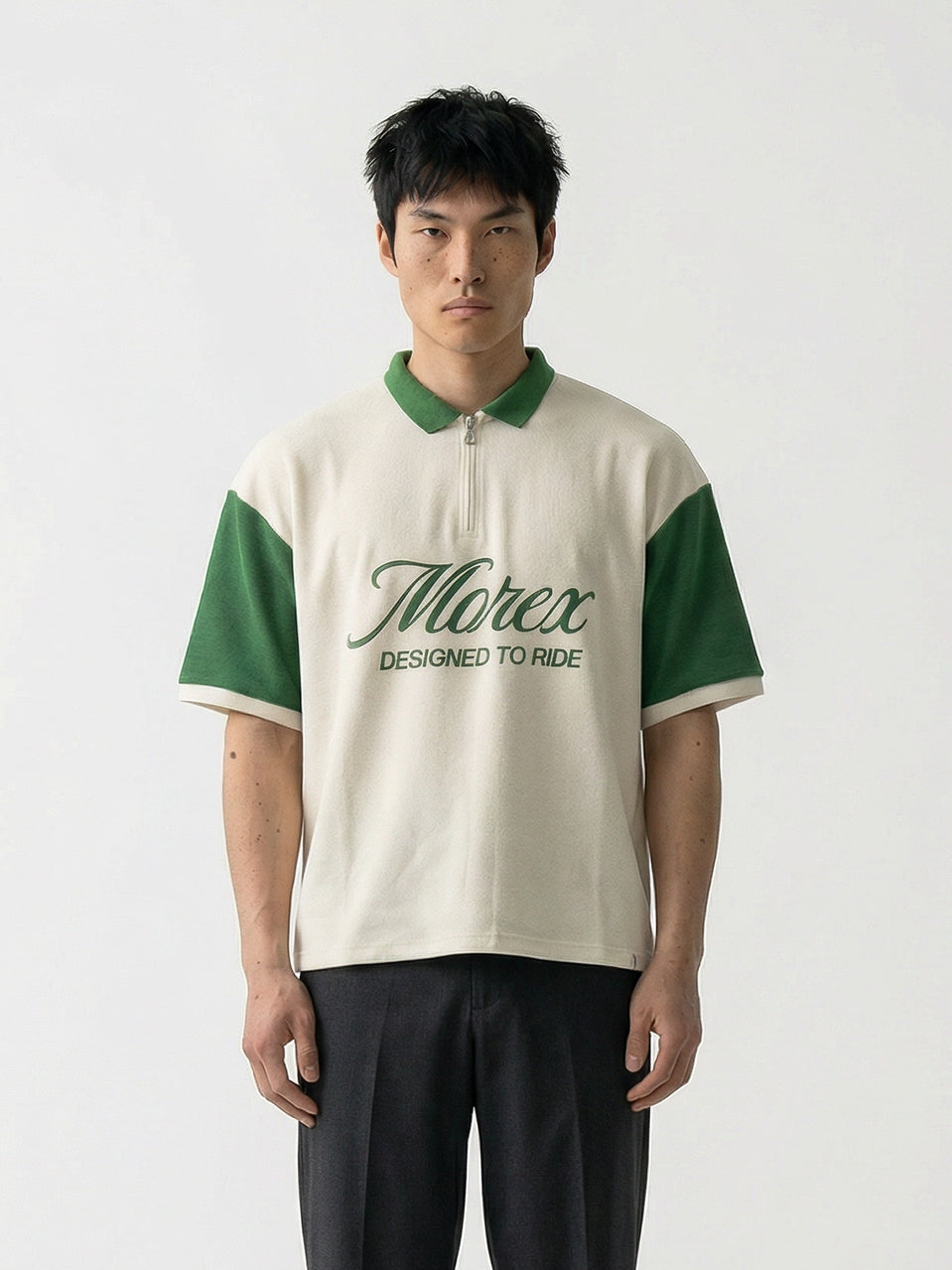 Homme portant un polo Morex Custom blanc cassé avec manches et col verts, logotypé Morex sur la poitrine, associé à un pantalon noir.