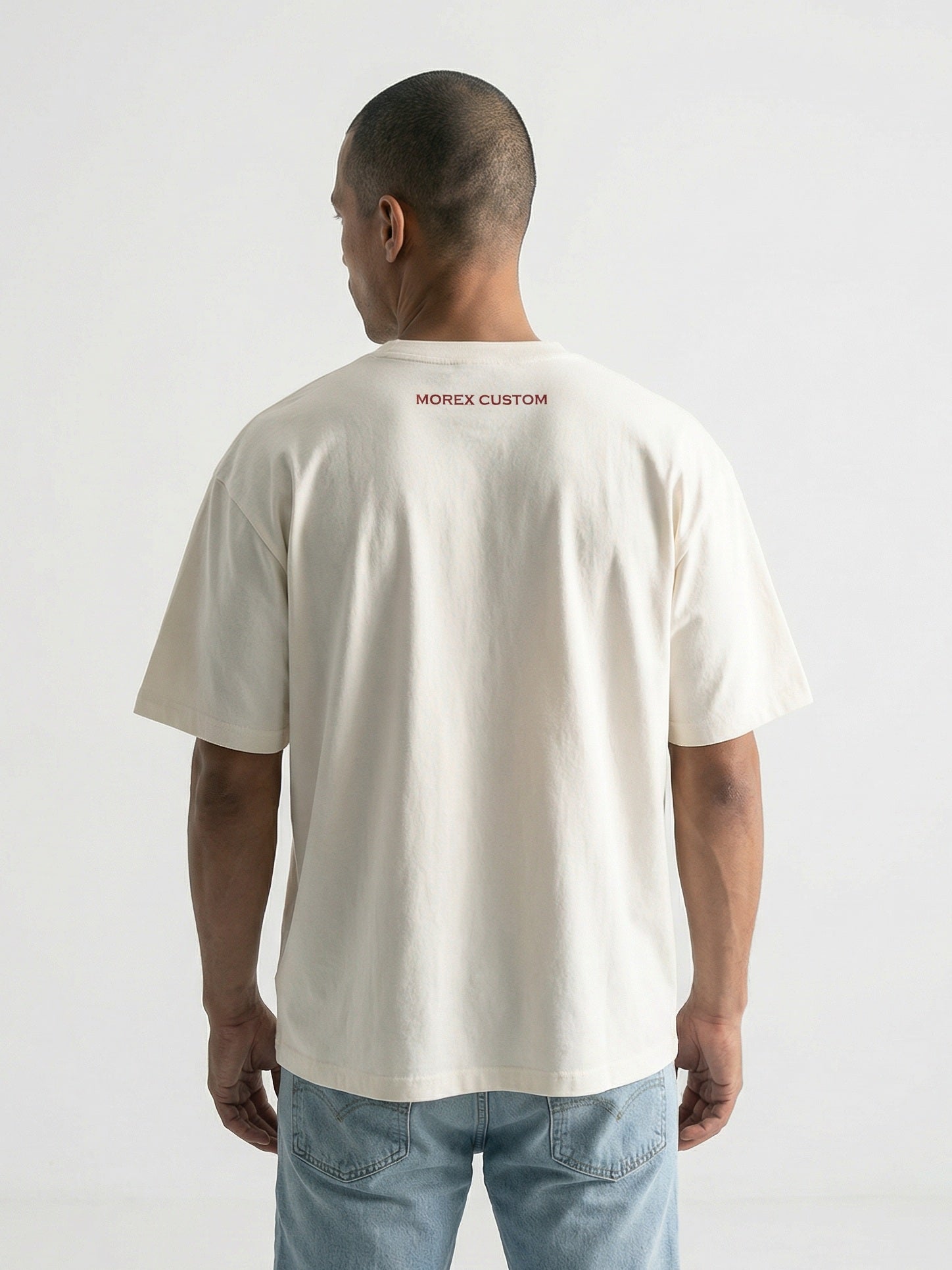 Vue de dos d'un homme portant un t-shirt beige crème Morex Custom avec logo rouge discret, style lifestyle moto.