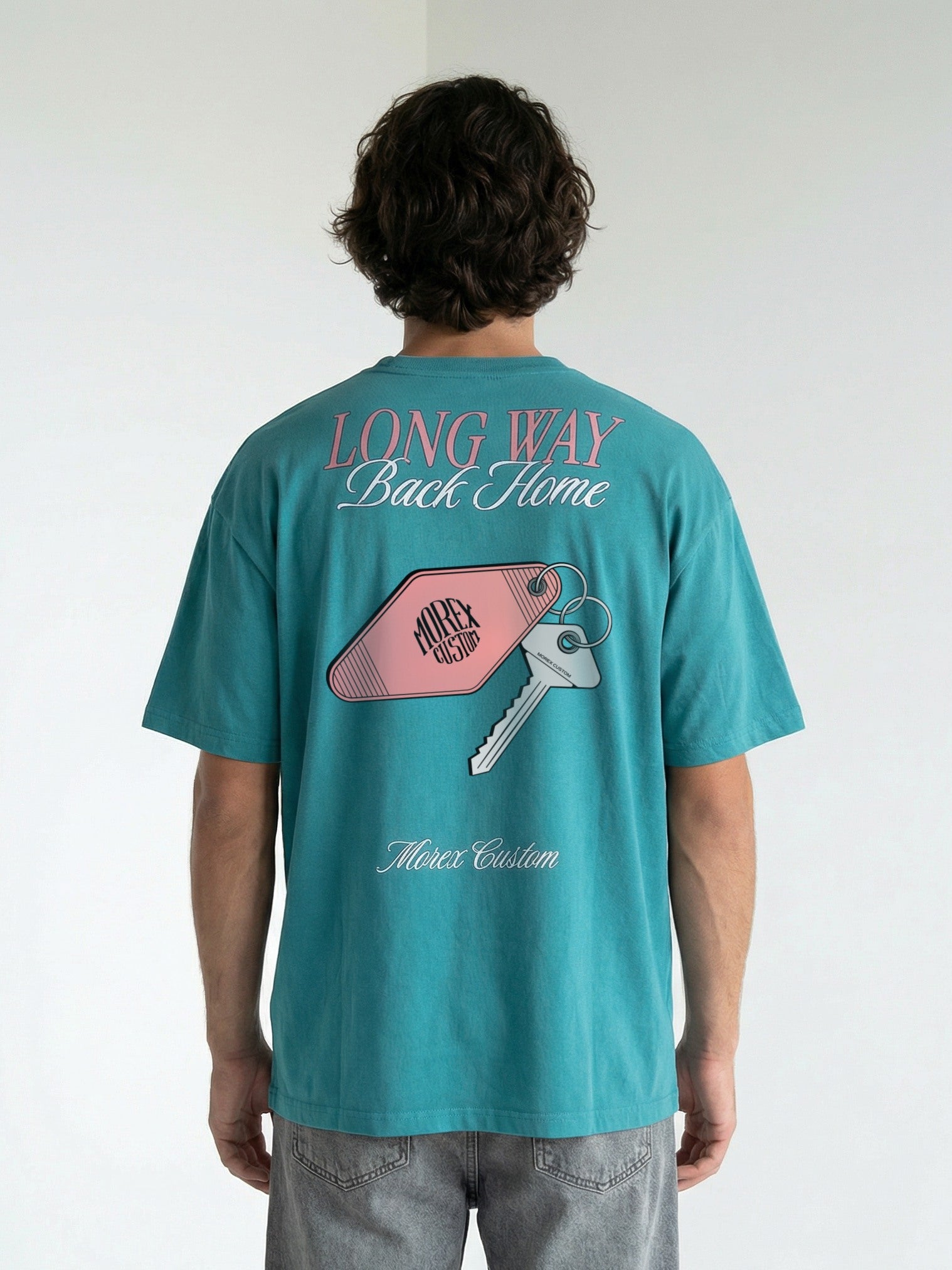 Vue de dos du t-shirt Morex Custom couleur bleu pétrole avec le graphisme Long Way Back Home illustrant une clé et un porte-clés de motel rose.