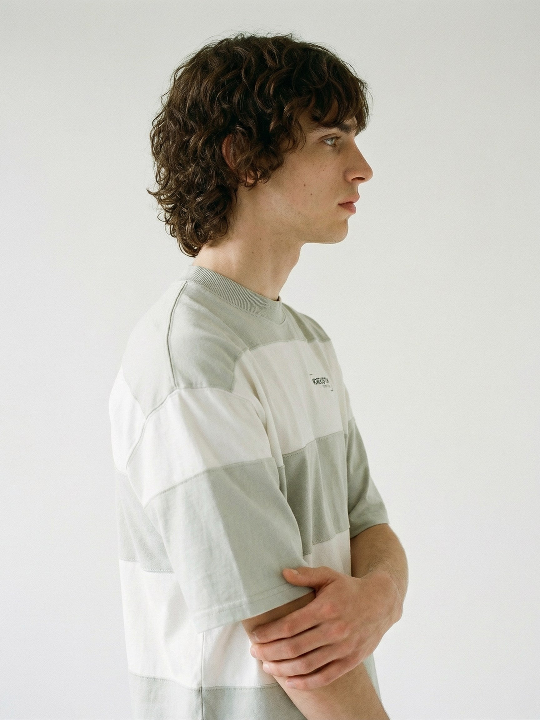 Homme de profil portant un t-shirt Morex Custom à larges rayures horizontales blanches et grises, style lifestyle décontracté.