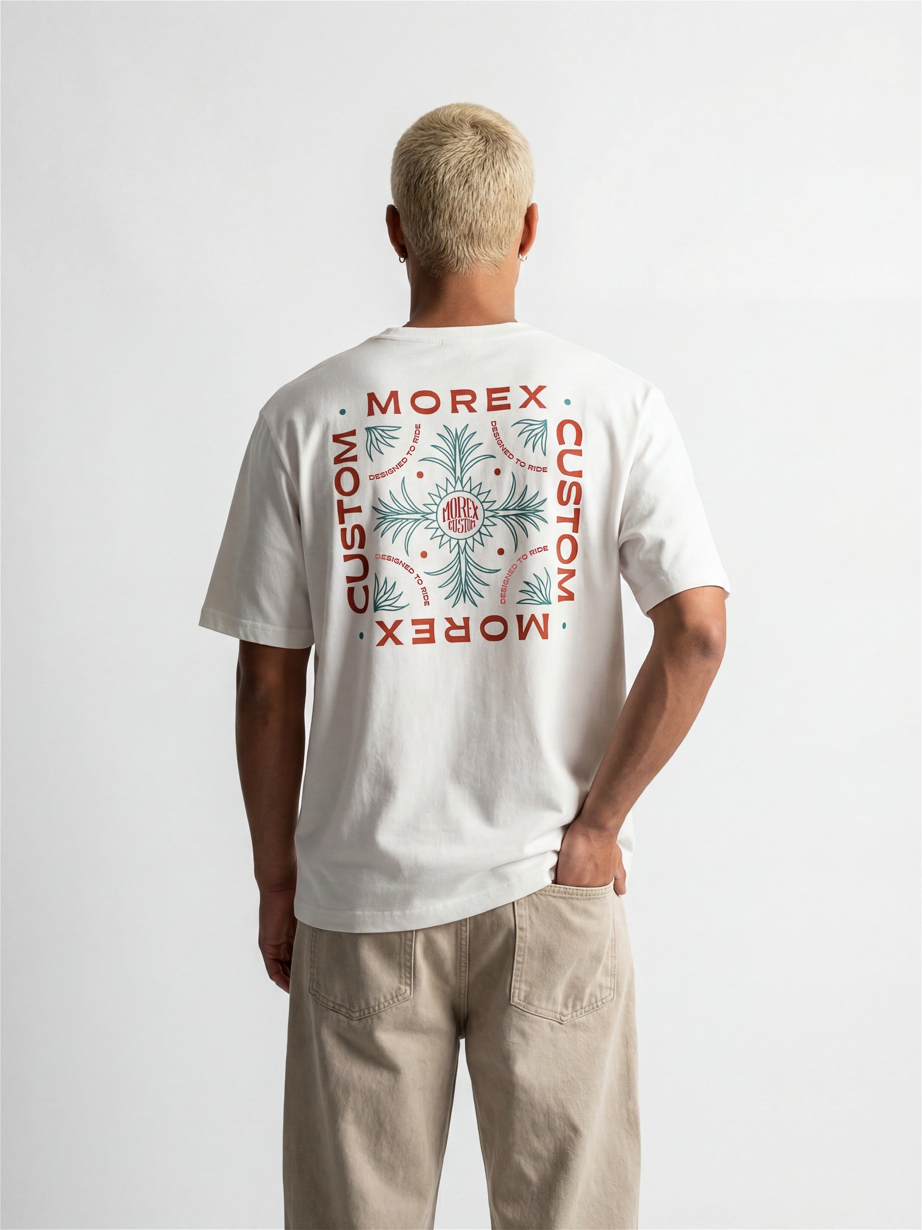 Vue de dos d'un homme portant un t-shirt blanc Morex Custom avec un design graphique carré et lettrage vintage.