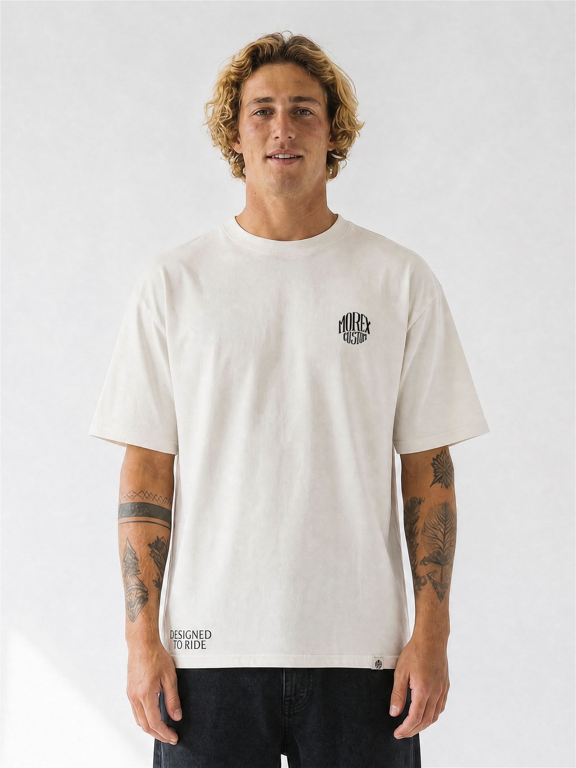 Homme portant un t-shirt oversize blanc cassé Morex Custom au style moto lifestyle avec un jean brut.