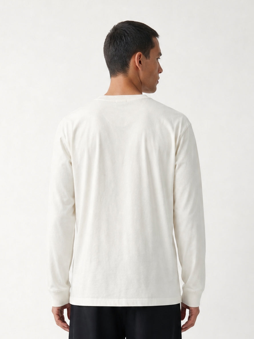 Homme de dos portant un t-shirt à manches longues blanc cassé et un pantalon noir fluide, style minimaliste et décontracté de la collection Morex Custom.