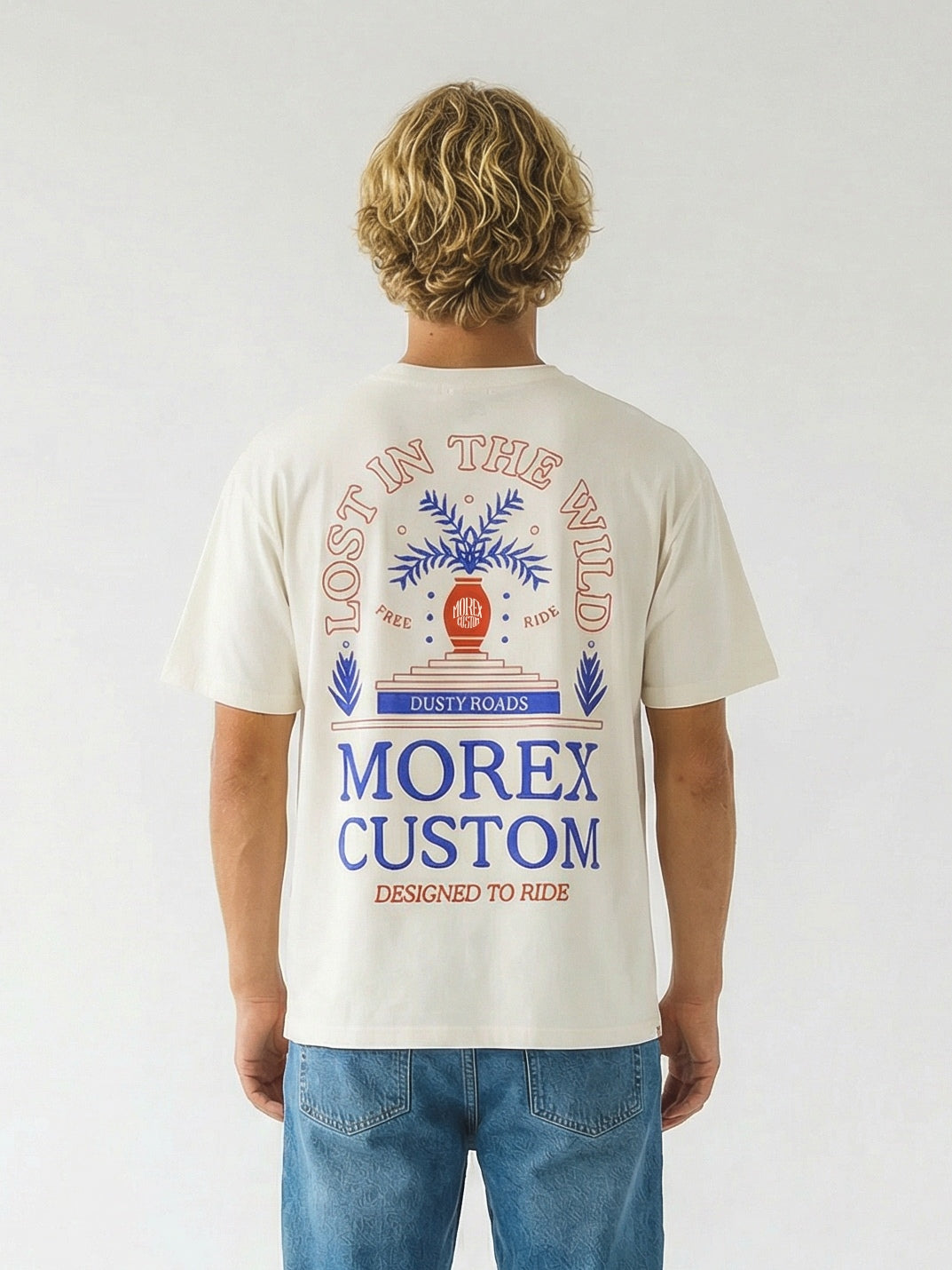 Vue de dos d'un homme portant un t-shirt Morex Custom blanc cassé avec une illustration graphique colorée et l'inscription 'Morex Custom Destined to Wear', assorti à un jean bleu.