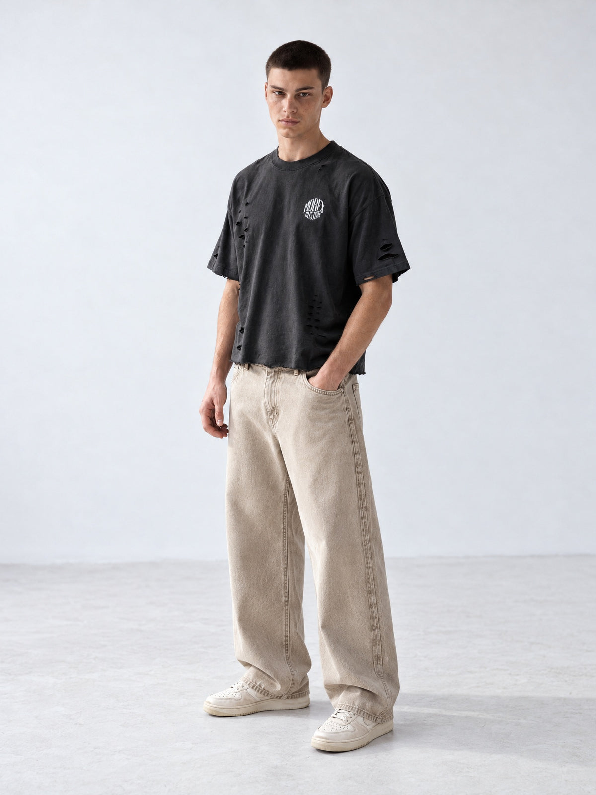 Homme portant un t-shirt oversize noir délavé effet vieilli et usé Morex Custom avec un jean ample beige, look streetwear moto lifestyle.