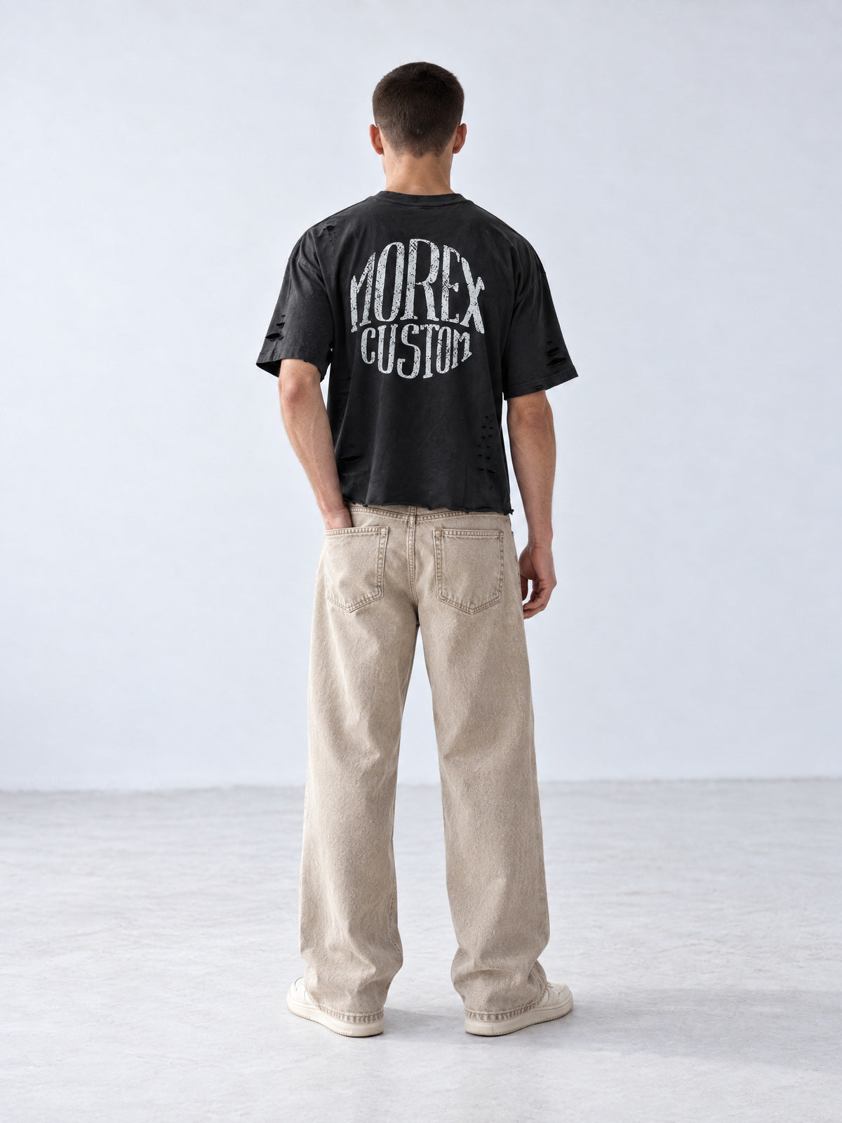 Vue arrière du t-shirt oversize noir délavé Morex Custom avec logo vintage au dos, associé à un pantalon beige large style streetwear moto.