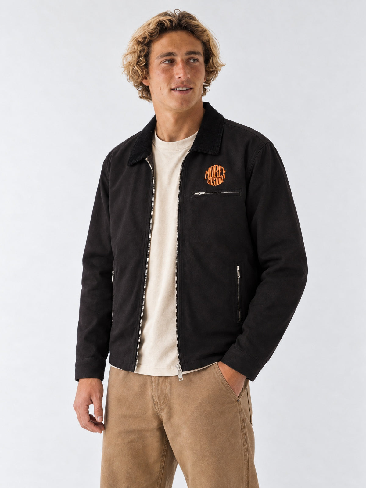 Homme portant la veste zippée noire en toile Morex Custom avec logo orange brodé sur la poitrine, style moto lifestyle et workwear